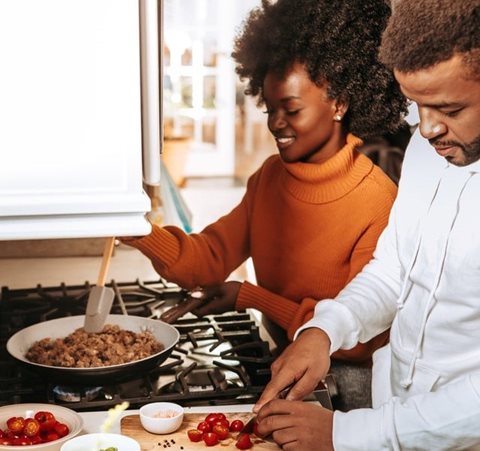 a couple cooking together in the kitchen